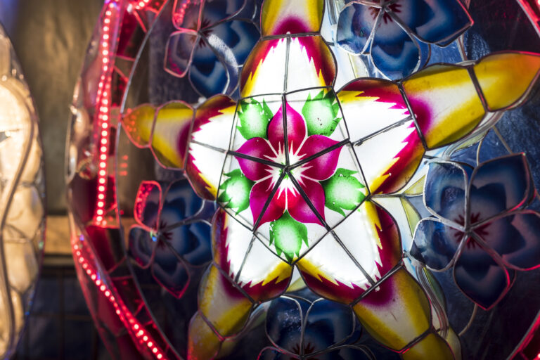A Parol for sale at a stand at nighttime. A Filipino ornamental lantern displayed during the Christmas season. Made with capiz shells, led lights and bamboo.