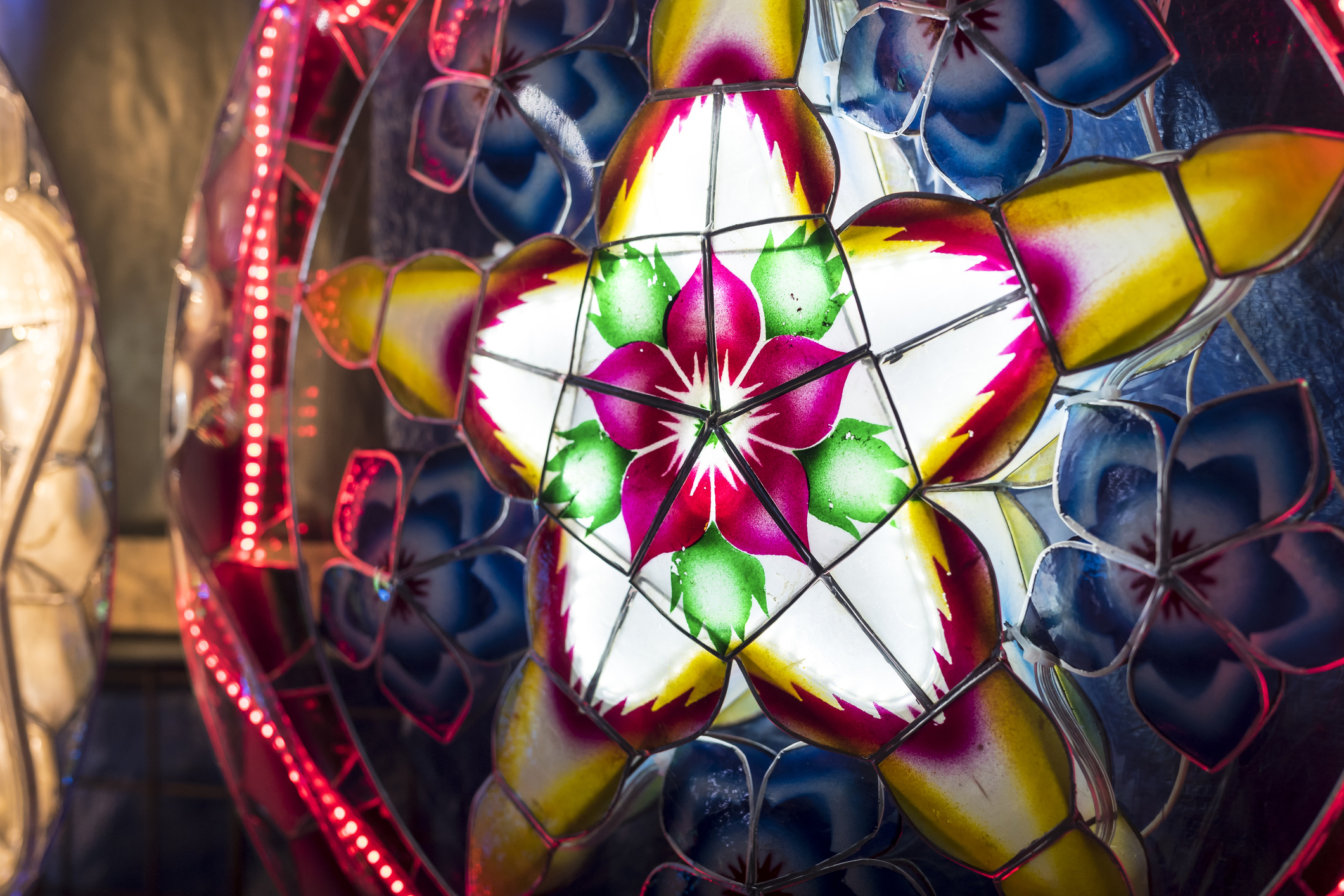 A Parol for sale at a stand at nighttime. A Filipino ornamental lantern displayed during the Christmas season. Made with capiz shells, led lights and bamboo.